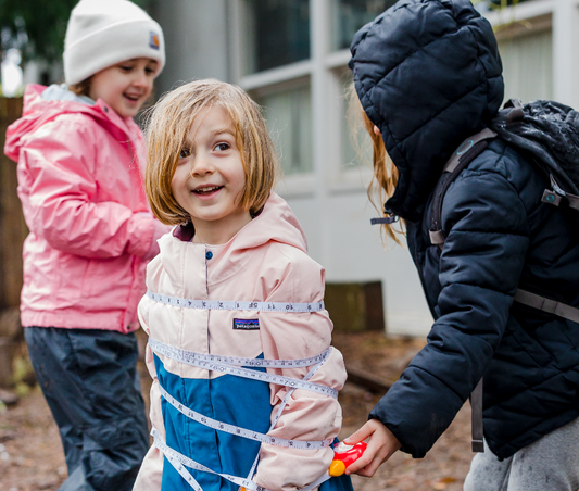 Kids playing in backyard wrapping with flexible tape measure